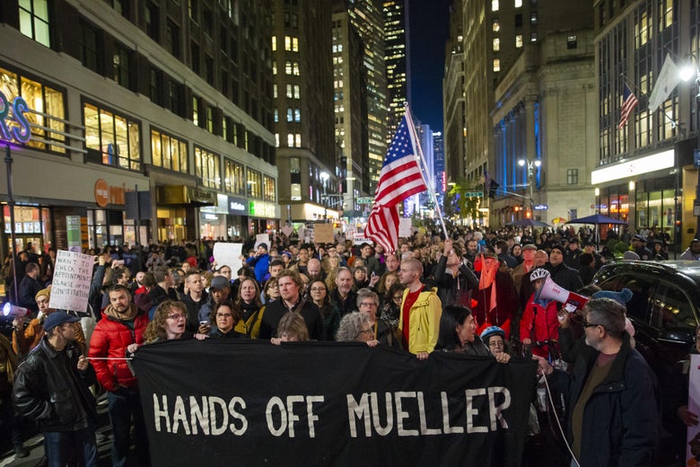 Protesters walk through Times Square with a banner that says "Hands Off Mueller."